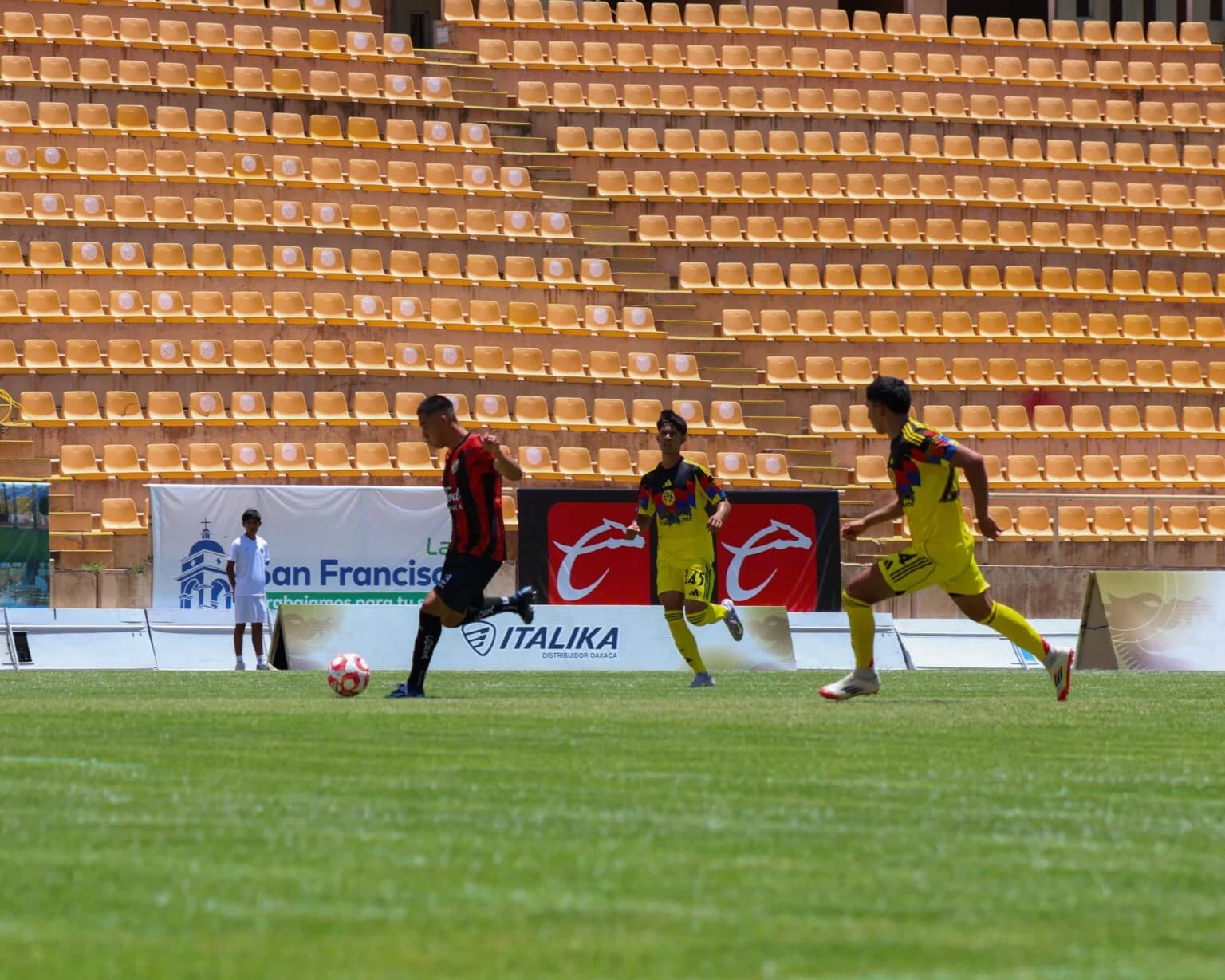 Un jugador de Dragones conduce el balón ante dos rivales del América en la Copa Promesas.