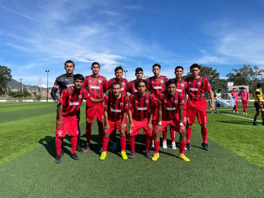 Once inicial de Dragones, con uniforme rojinegro, posa en la cancha antes del partido.