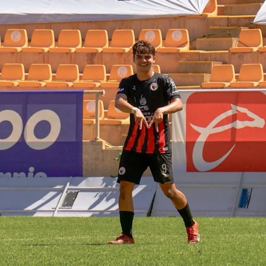 Santiago Alva celebra un gol frente a la tribuna, sonriendo y señalándose la playera.